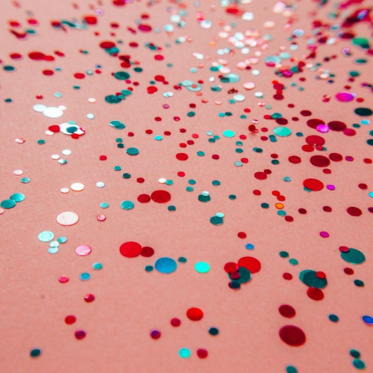 Zu viele Themen, keine Linie Bunte Glitzerpartikel auf einem rosa Hintergrund verstreut.